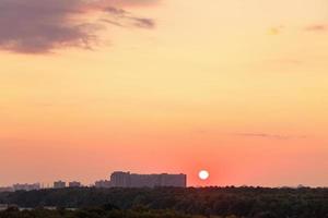 Sonne über dem Horizont während des roten Sonnenaufgangs über der Stadt foto