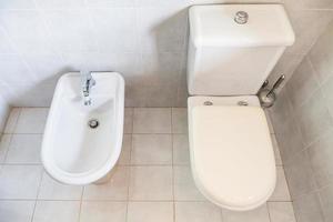 Weiße Toilette mit Beckenablauf und Bidet foto