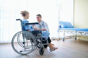 Ein Arzt spricht mit einem Patienten im Rollstuhl