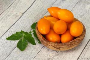 gelber Tomatenhaufen in der Holzschale foto