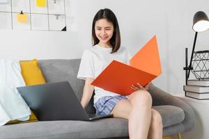 Frau, die von zu Hause auf dem Sofa arbeitet foto