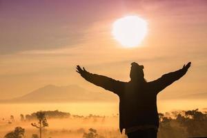 Silhouette von Frauen mit erhobenen Armen vor Sonnenuntergang foto