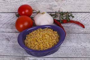 Roher Bulgur in der Schüssel mit Tomaten und Knoblauch foto