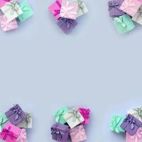 Stapel von kleinen farbigen Geschenkboxen mit Bändern liegen auf violettem Hintergrund foto
