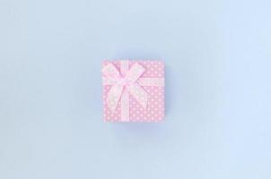 kleine rosa geschenkbox mit band liegt auf violettem hintergrund foto