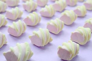 bunter Marshmallow auf violettem Papierhintergrund. pastellfarbenes, kreatives Strukturmuster. perspektivische Makroaufnahme foto