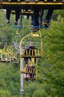 Menschen fahren mit einer Seilbahn. die beine der passagiere hängen über dem bergwald foto