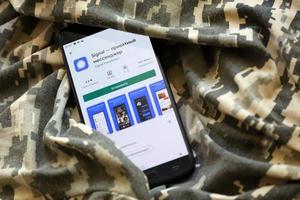 ternopil, ukraine - 24. april 2022 signalisieren private messenger-app-play-store-seite auf dem display eines schwarzen mobilen smartphones auf ukrainischer militärischer tarnung foto