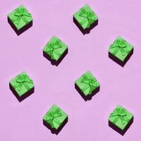 viele kleine grüne geschenkboxen auf texturhintergrund aus modetrendigem pastellrosa farbpapier foto