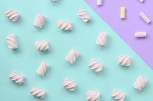 bunter Marshmallow auf violettem und blauem Papierhintergrund. pastellfarbenes, kreatives Strukturmuster. minimal foto