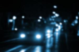 verschwommene Nachtszene des Verkehrs auf der Fahrbahn. defokussiertes Bild von Autos, die mit leuchtenden Scheinwerfern fahren. Bokeh-Kunst foto