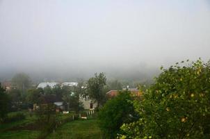 Das Mehrfamilienhaus liegt vor einer dicken Nebelschicht. leben in einer bergigen gegend in den karpaten, ukraine foto
