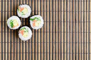 Sushi-Rollen liegen auf einer Nähmatte aus Bambusstroh. traditionelles asiatisches essen. Ansicht von oben. flacher Laienminimalismus mit Kopierraum