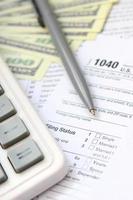 Der Stift, das Notizbuch, der Taschenrechner und die Dollarscheine befinden sich auf dem Steuerformular 1040 US-Einzeleinkommensteuererklärung. die Zeit, Steuern zu zahlen foto