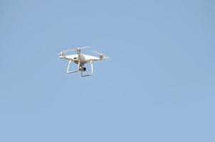 große weiße Drohne, die in einem hellen, wolkenlosen blauen Himmel schwebt foto