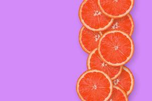 Reihe von Grapefruitscheiben auf hellviolettem Hintergrund foto