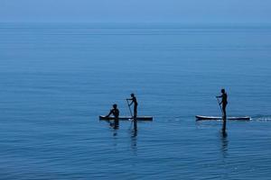 Eine Gruppe von Leuten fährt ein Sup-Board. Hobby, Freizeit, Sport foto