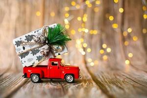 Miniaturauto auf hölzernem Hintergrund mit Weihnachtslicht, Weihnachtsgeschenk. foto