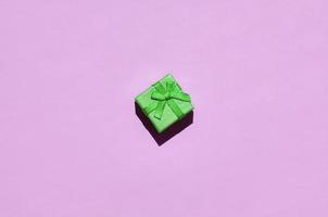 kleine grüne geschenkbox liegen auf texturhintergrund von modischem pastellrosa farbpapier foto