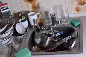 ein riesiger Stapel ungewaschenen Geschirrs in der Küchenspüle und auf der Arbeitsplatte foto