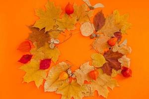 Kranzrahmen aus trockenen Blättern auf orangefarbenem Hintergrund foto