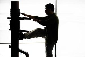 Silhouette eines Fighter Wing Chun und einer Holzpuppe auf einem Hintergrund. Wing Chun Kung Fu Selbstverteidigung foto