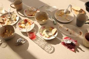 Leere schmutzige Teller mit Löffeln und Gabeln nach dem Essen auf dem Tisch. Bankettabschlusskonzept. ungewaschenes Geschirr foto