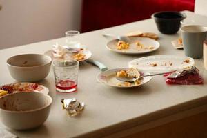 Leere schmutzige Teller mit Löffeln und Gabeln nach dem Essen auf dem Tisch. Bankettabschlusskonzept. ungewaschenes Geschirr foto