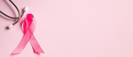 Brustkrebs-Aufklärungsmonat. Rosa Schleife und Stethoskop auf farbigem Hintergrund. Frauengesundheitskonzept. Symbol des Kampfes gegen die Onkologie. foto