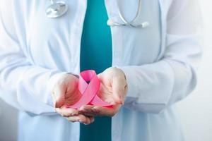 Brustkrebs-Aufklärungsmonat. ärztin in medizinischer weißer uniform hält rosa band in ihren händen. Frauengesundheit foto