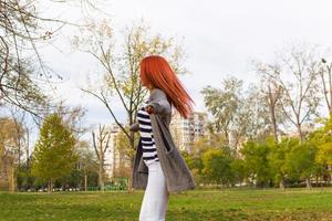 Verspielte Frau, die sich während der Herbstsaison mit ausgestreckten Armen dreht. foto