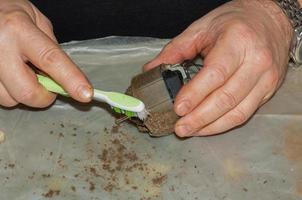 Einen sehr schmutzigen Küchenabluftventilator mit einer Bürste von Schmutz befreien. Ein Mann reinigt die Teile eines Lüfters mit einer Bürste foto