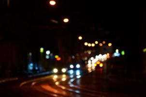 verschwommene Nachtszene des Verkehrs auf der Fahrbahn. defokussiertes Bild von Autos, die mit leuchtenden Scheinwerfern fahren. Bokeh-Kunst foto