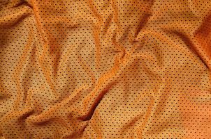 orange sportbekleidung stoff textur hintergrund. Draufsicht der orangefarbenen Textiloberfläche. helles Basketballshirt. Textraum foto