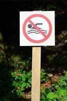 eine Säule mit einem Schild, das auf ein Schwimmverbot hinweist. das Schild zeigt eine durchgestrichene schwebende Person foto