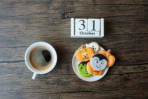 glücklicher halloween-tag mit keksen, kaffee und kalender vom 31. oktober auf weißem hintergrund. trick oder bedrohung, hallo oktober, herbst, festliches, party- und urlaubskonzept foto