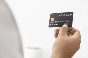 nahaufnahmehand des asiatischen mannes, der schwarze kreditkarte in seiner hand hält. isoliert auf weißem Hintergrund. konzept von finanzen, handel, kommunikation, sozial, technologie, business foto