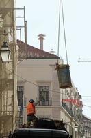 lissabon, portugal, 2019 - arbeiter auf einer baustelle in lissabon, der die bewegung des krans oben leitet foto