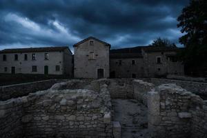 Antike Ruinen in der archäologischen Stätte einer alten römischen Stadt in Mittelitalien, alte europäische Architektur, die an einem dunklen, düsteren Abend mit bewölktem Himmel aufgegeben wurde foto