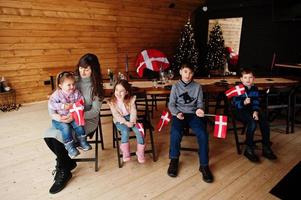 familie mit dänemark-flaggen im holzhaus, das am tisch sitzt. reise in die skandinavischen länder. die glücklichsten Dänen. foto