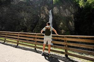 Rücken des Mannes mit Rucksack gegen Wasserfall in Liechtensteinklamm oder Liechtensteinklamm, Österreich. foto