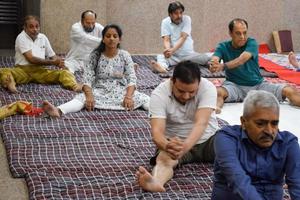 neu-delhi, indien, 19. juni 2022 - gruppen-yoga-übungssitzung für menschen verschiedener altersgruppen im balaji-tempel, vivek vihar, internationaler yoga-tag, große gruppe von erwachsenen, die an yoga-kursen im tempel teilnehmen foto