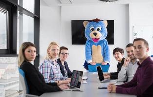 als bär verkleideter chef hat spaß mit geschäftsleuten im trendigen büro foto