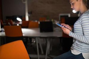 Frau, die im Nachtbüro an einem digitalen Tablet arbeitet foto