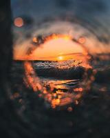 Wassertropfen auf einem kreisförmigen Glas während des Sonnenuntergangs foto