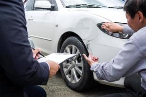 Agent, der das Versicherungsformular in der Nähe eines beschädigten Autos einreicht foto