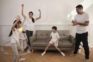 happy wellness asian thai family, eltern und kinder haben spaß beim gemeinsamen hula-hoop-spielen, fitnesstraining und gesunder übung im weißen wohnzimmer, häuslichem lebensstil und wochenendaktivitäten. foto