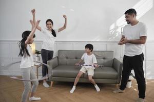 happy wellness asian thai family, eltern und kinder haben spaß beim gemeinsamen hula-hoop-spielen, fitnesstraining und gesunder übung im weißen wohnzimmer, häuslichem lebensstil und wochenendaktivitäten. foto