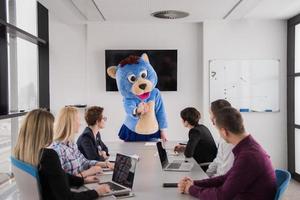 als bär verkleideter chef hat spaß mit geschäftsleuten im trendigen büro foto