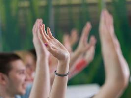 studentengruppe hebt die hände in der klasse foto